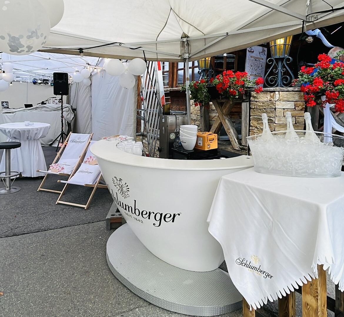 An outdoor tent with an elegant reception desk and floral arrangements. The area appears to be prepared for an event or celebration.