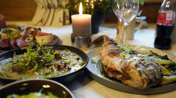 Ein gedeckter Tisch mit köstlichem Essen. Gegrillter Fisch liegt neben einer Gemüse- und einer Salatschüssel.