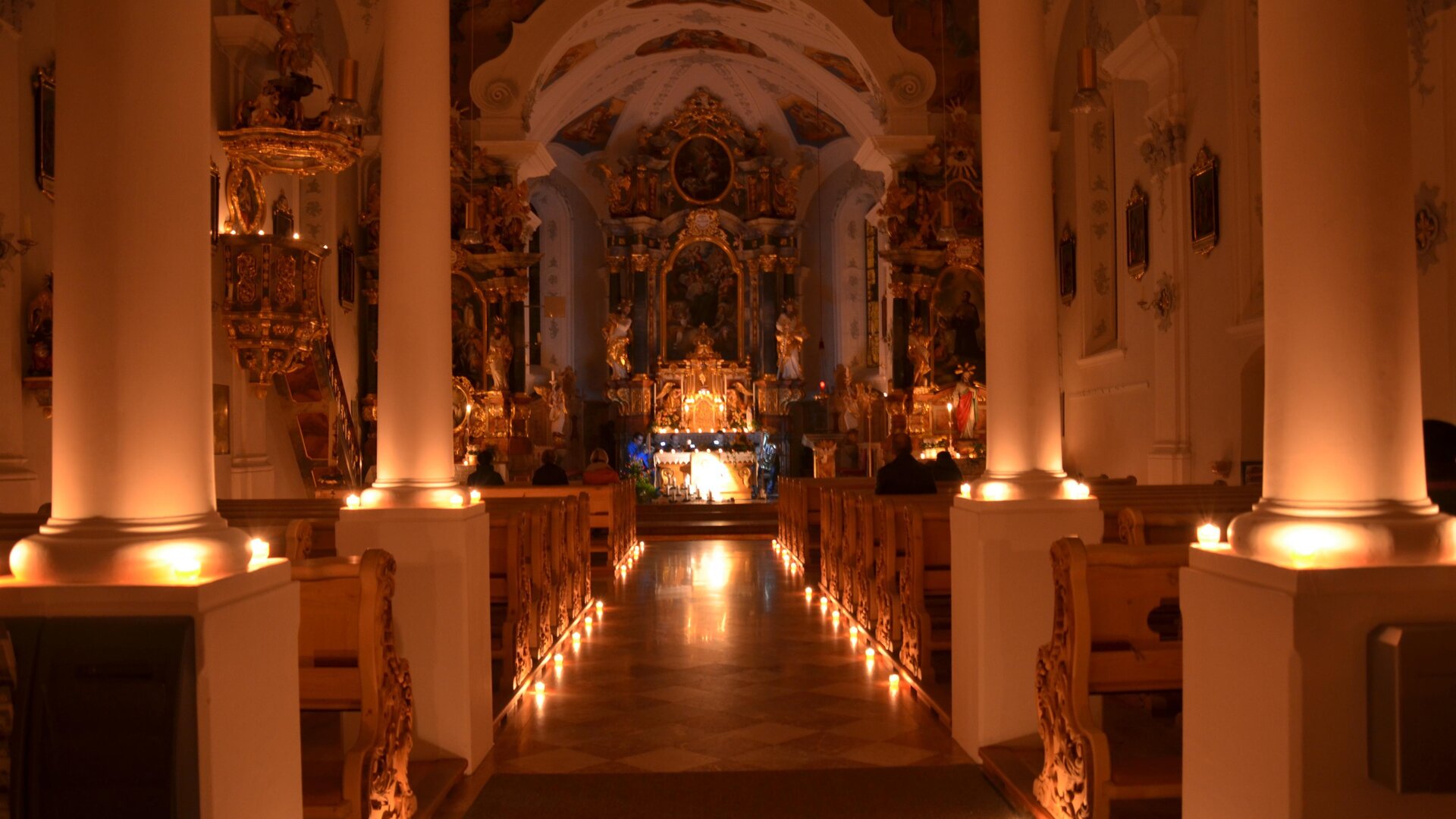 A beautiful church with soft lighting and an impressive altar arrangement. The space radiates a calm and reflective atmosphere.