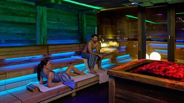 Ein entspannender Wellnessbereich mit sanften Beleuchtungseffekten. Eine Frau und ein Mann genießen die entspannende Atmosphäre in einer Sauna.