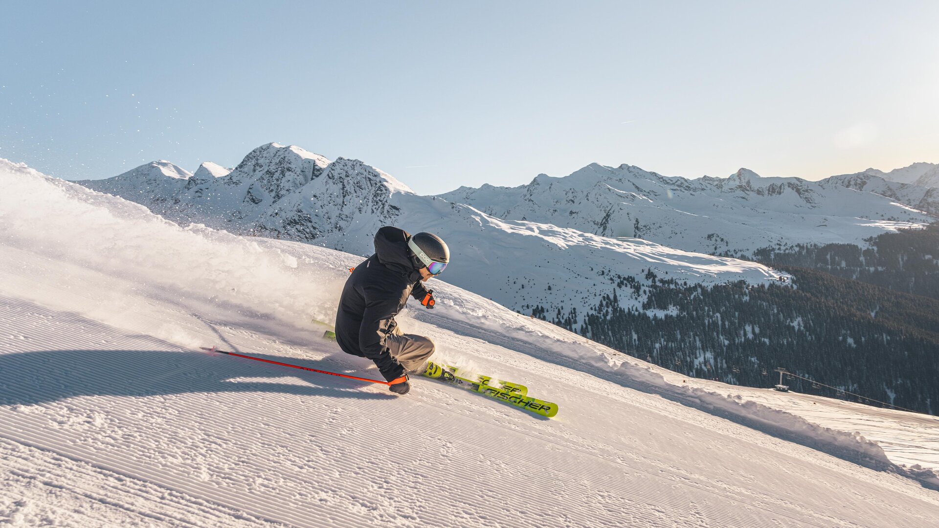 A skier is going down the snow-covered slope. In the background, majestic mountains are visible.
