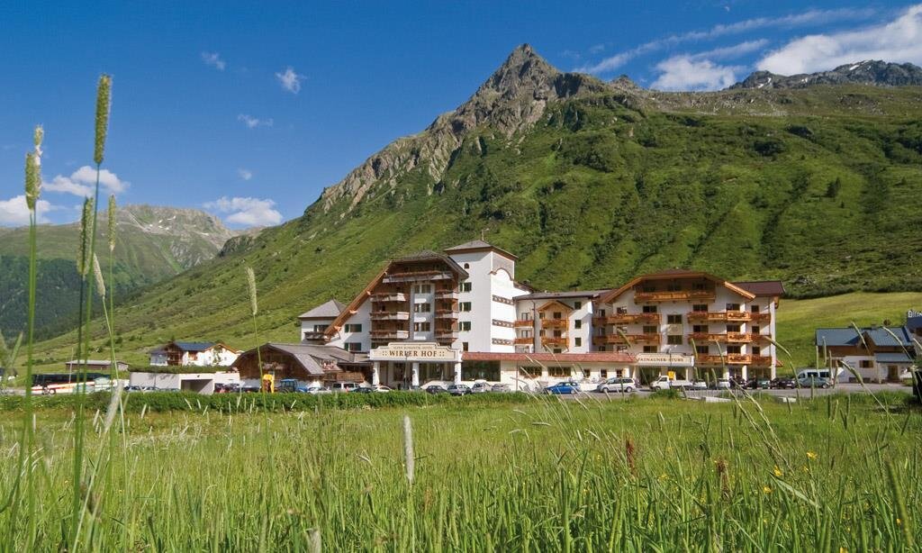Ein schönes Hotel in den Bergen mit grünen Wiesen und blauen Himmel. Die umliegende Landschaft ist malerisch und einladend.