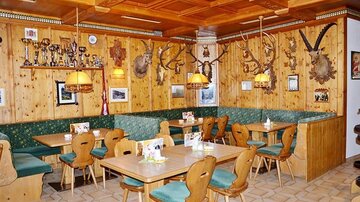 Ein gemütliches Restaurant mit Holzwänden und einer rustikalen Einrichtung. An den Wänden hängen verschiedene Trophäen und Erinnerungsstücke.