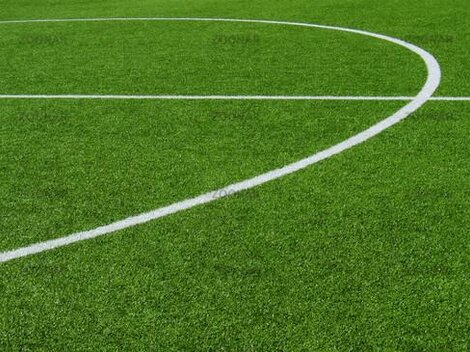 Eine Nahaufnahme eines Fußballfeldes mit grünem Kunstrasen. Die weißen Linien zeigen den Spielbereich an.