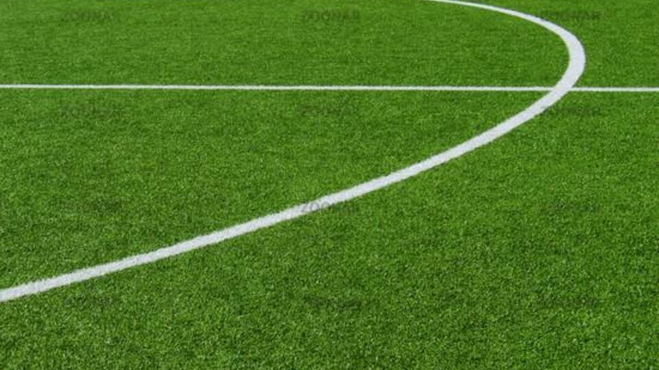 Eine Nahaufnahme eines Fußballfeldes mit grünem Kunstrasen. Die weißen Linien zeigen den Spielbereich an.