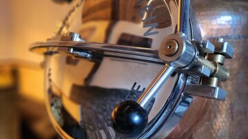 Ein glänzendes Messgerät aus Metall mit einer runden Anzeige. Die Details sind sorgfältig verarbeitet und reflektieren die Umgebung.