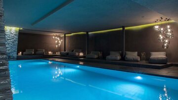 Ein eleganter Wellnessbereich mit einem beleuchteten Pool und komfortablen Liegen. Sanfte Beleuchtung schafft eine entspannende Atmosphäre.