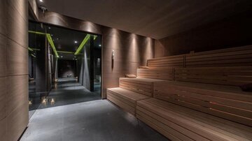 Ein modernes Wellnessambiente mit einer Holzsauna und gedimmtem Licht. Der Raum vermittelt eine entspannende Atmosphäre.