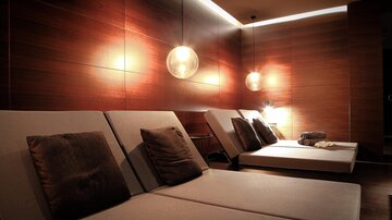 Ein entspannender Wellnessbereich mit bequemen Liegen und sanftem Licht. Die Holzverkleidung schafft eine warme und ruhige Atmosphäre.