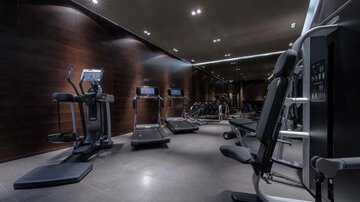 Ein modernes Fitnessstudio mit verschiedenen Fitnessgeräten. Der Raum hat eine elegante Atmosphäre mit gedämpftem Licht.