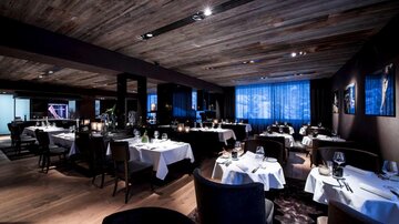 Ein stilvolles Restaurant mit eleganten Tischen und gedämpftem Licht. Die Atmosphäre ist modern und einladend.