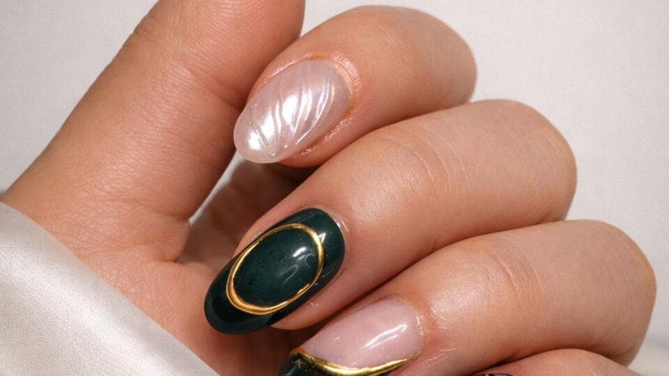 Eine Hand mit kunstvoll gestalteten Nägeln in verschiedenen Farben. Die Nägel sind mit goldenen und schwarzen Details verziert.