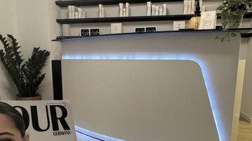Ein moderner Empfangsbereich mit einem stilvollen, beleuchteten Tresen. Im Vordergrund liegt ein Magazin, das sich auf Schönheitsthemen konzentriert.
