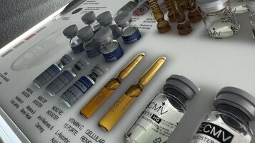 Eine Sammlung von Injektionsfläschchen und Ampullen auf einem Labortisch. Die Fläschchen sind unterschiedlich beschriftet und enthalten diverse Lösungen für medizinische Anwendungen.