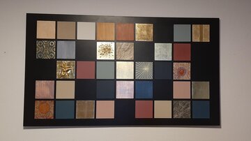 Eine Sammlung von Farbmusterplatten auf einer schwarzen Tafel. Die Platten zeigen verschiedene Texturen und Farben, die für Design und Dekoration verwendet werden können.