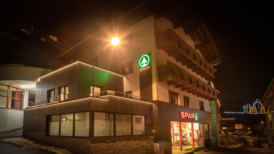 Ein Geschäft mit hellem Licht bei Nacht. Es ist ein SPAR-Markt in einem modernen Gebäude.