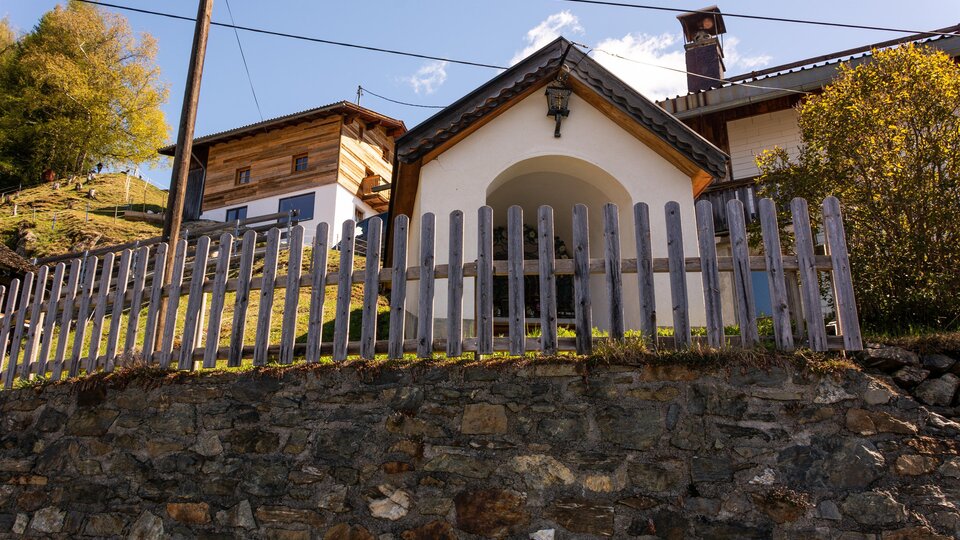 Ein charmantes Haus mit einem Holzzaun und einer malerischen Lage. Umgeben von Natur und Bergen, strahlt es Gemütlichkeit aus. | © Bernhard Gruber – Photography