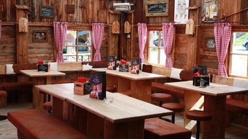 Ein gemütliches Restaurant mit Holzvertäfelung und rustikalen Tischen. Die Fenster sind mit karierten Vorhängen dekoriert und es gibt Zeichen an den Wänden.